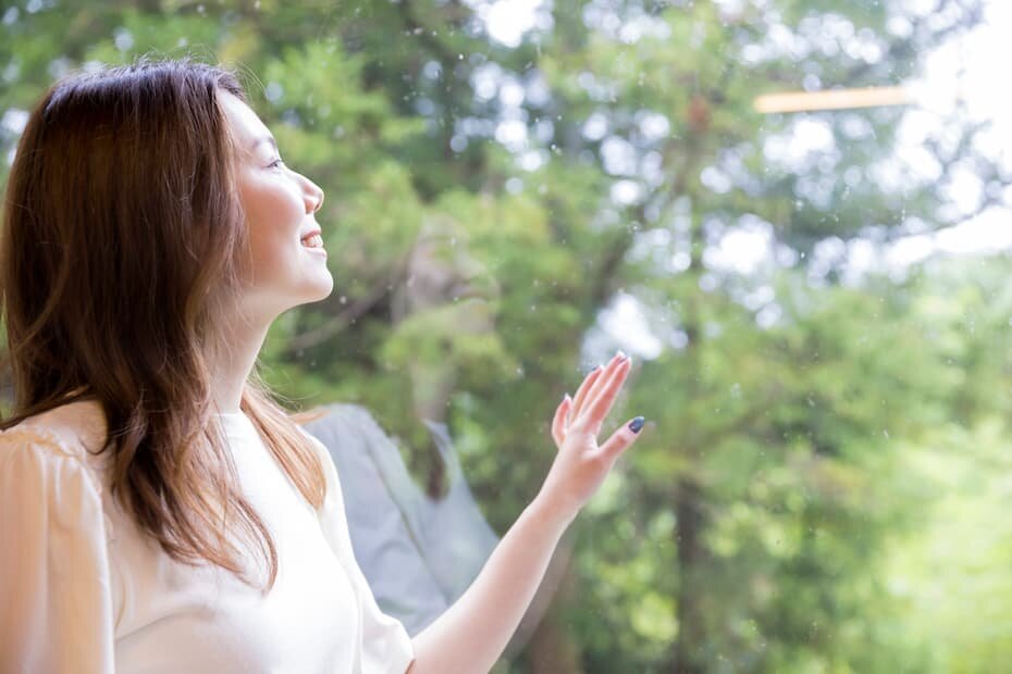 雨の降る中、窓から外の景色を眺める女性