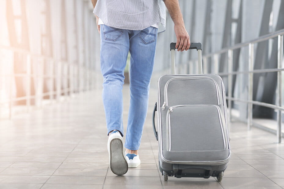 荷物を持って歩く後ろ姿の男性