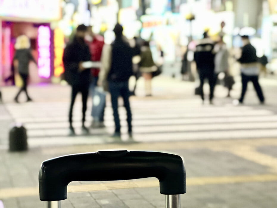 夜の町を歩く人々とキャリーバッグ